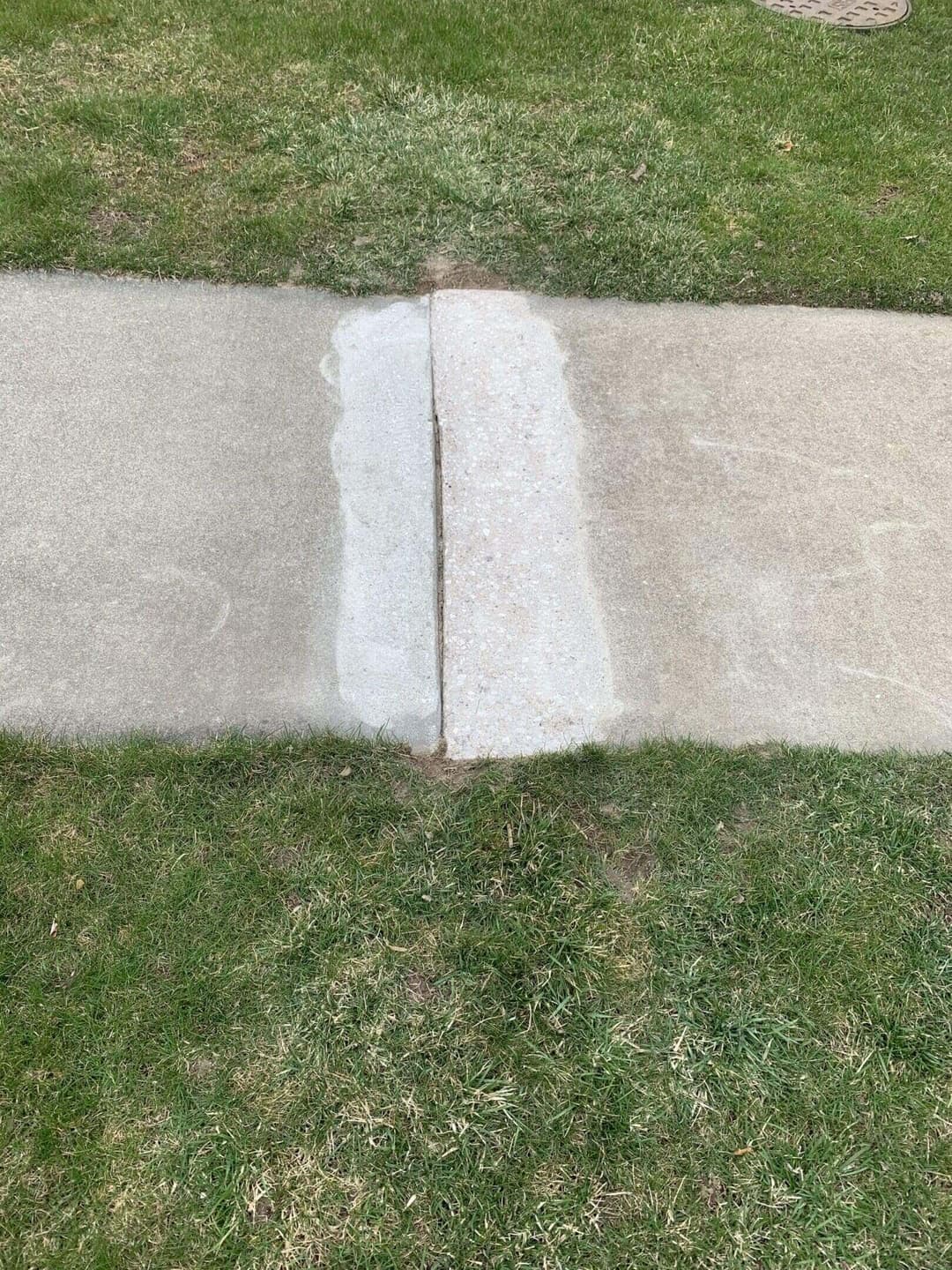 Uneven sidewalk patch before concrete repair